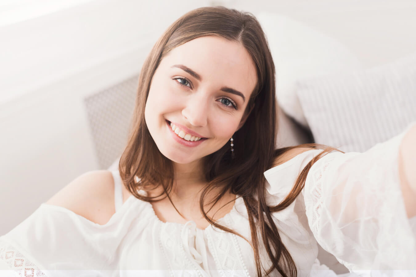 Pretty smiling girl making selfie, long-haired brunette in white clothes, close up